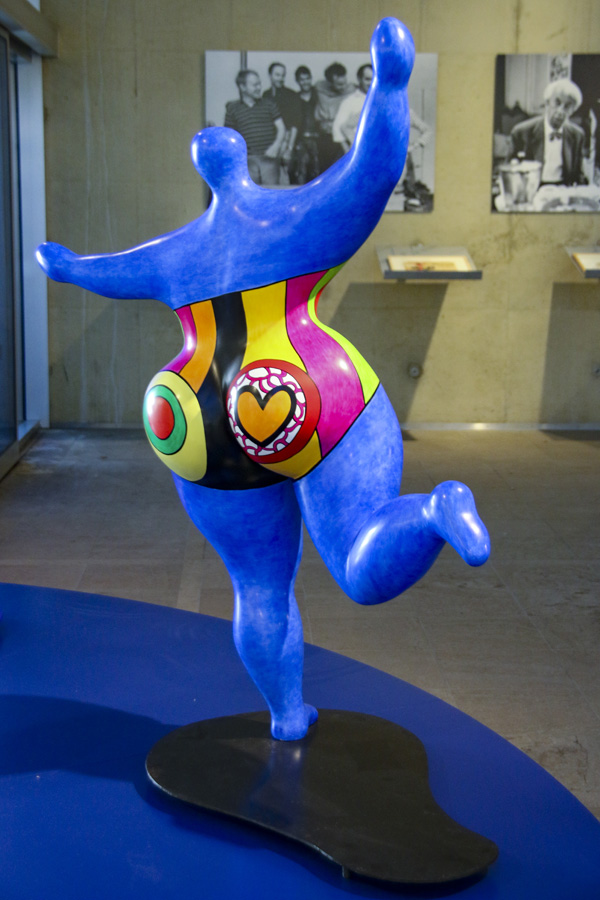 Blauwe Nana met op de achtergrond foto's uit het Stedelijk Museum, jaren zestig