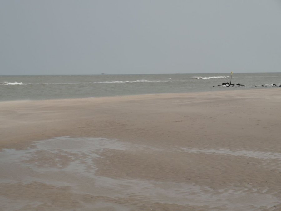 Strand en zee met een schip aan de horizon